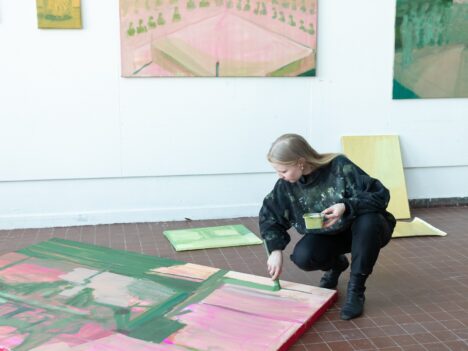 Kvinna målar på en stor duk på golvet