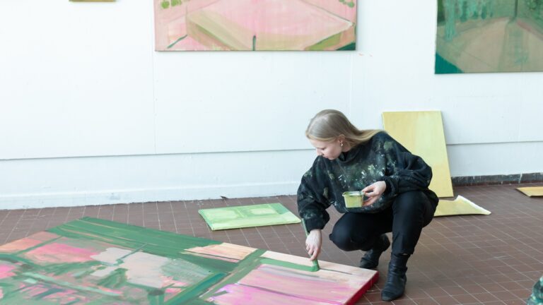 Kvinna målar på en stor duk på golvet