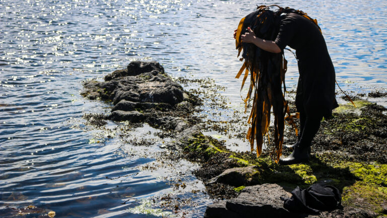 Kvinna vid strand med sjögräs i håret