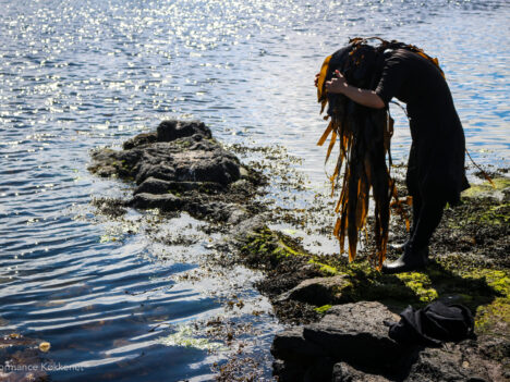 Kvinna vid strand med sjögräs i håret