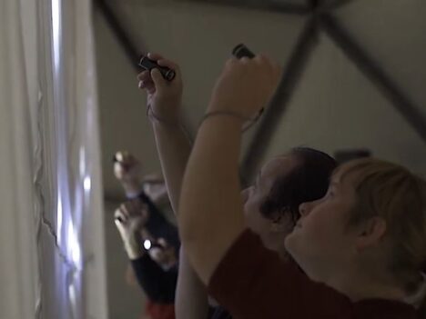 Sex personer skapar ljuskonst genom att rikta ficklampor mot ett vitt lakan.