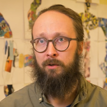 Gustav Person, taustalla seinä täynnä piirustuksia.