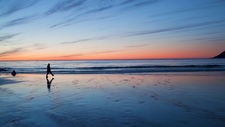 A man walks on the beach in the sunset
