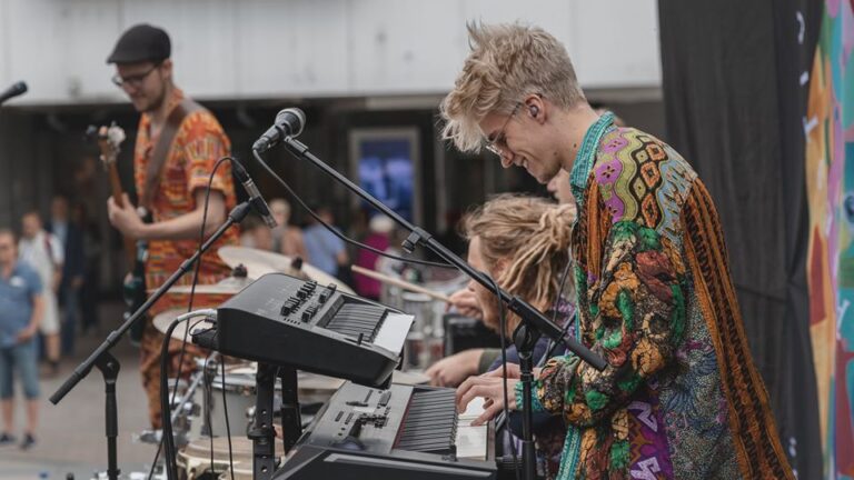 Smiling young man in a brightly coloured shirt playing the keyboard in a band.