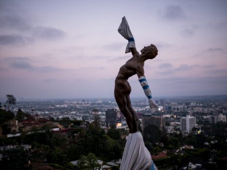 A statue overlooking a big city below.