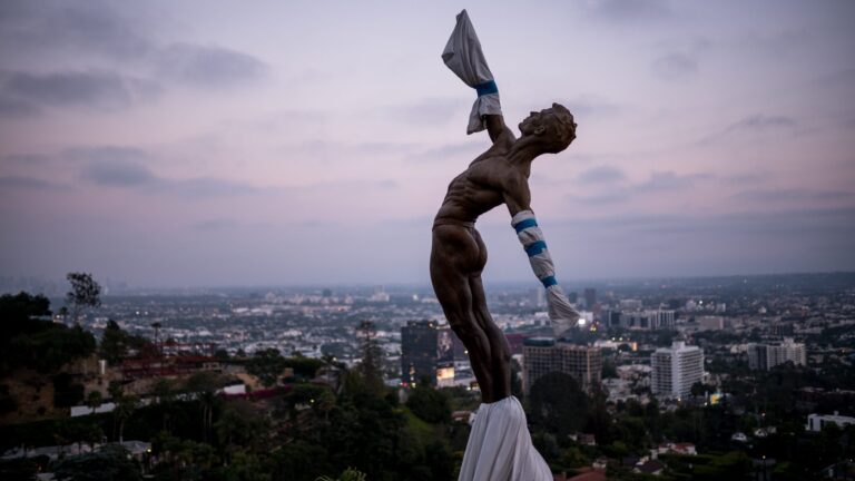A statue overlooking a big city below.