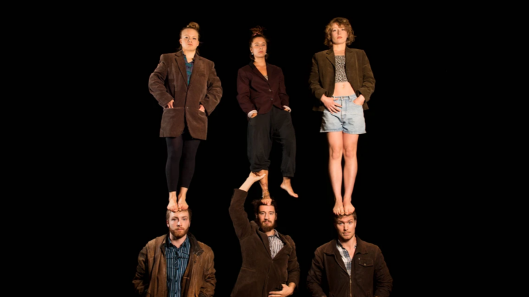 Tre män står på golvet, tre kvinnor står på deras huvuden.