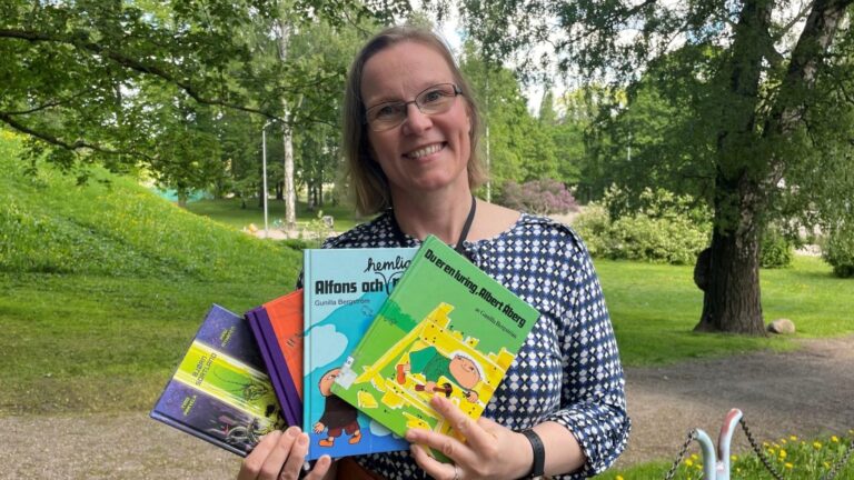 Mikaela Wickström poseeraa kirjojen kanssa puistossa