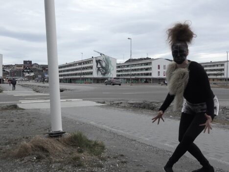 En traditionell Grönländsk maskdansare sminkad och klädd i svart går på gatan i Nuuk i Grönland