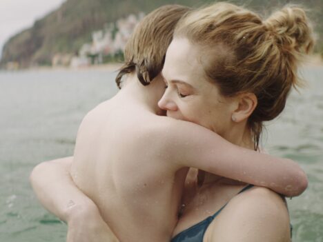 Mamma kramar om sitt barn vid en strand