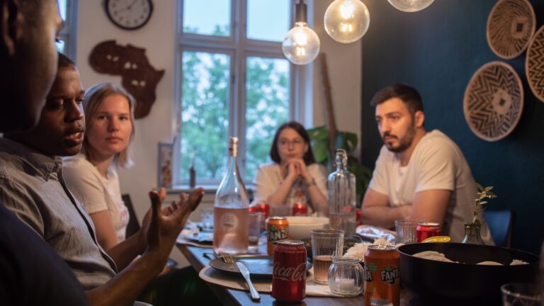 En grupp människor sitter vid ett middagsbord och diskuterar.