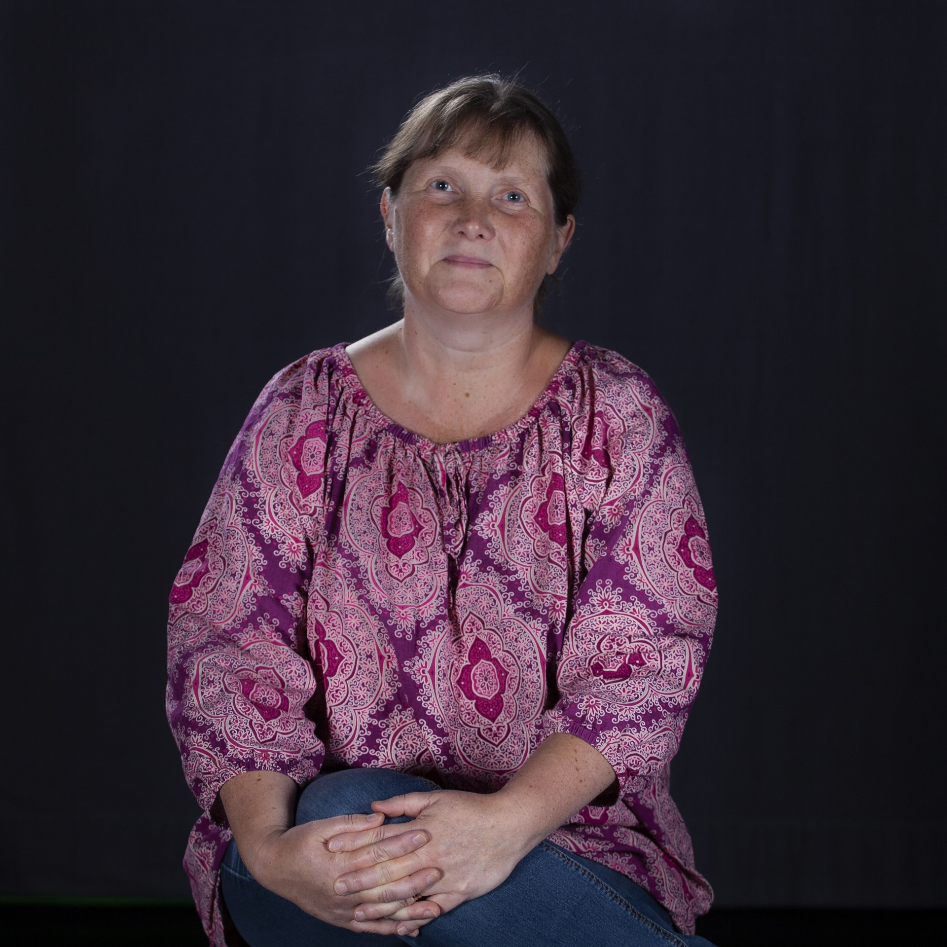 Porträtt av Marit Lindqvist. Medelålders kvinna iklädd en rosa mönstrad blus.
