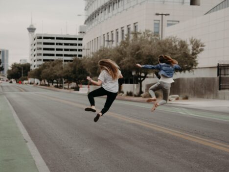 Two girls jumping in the street