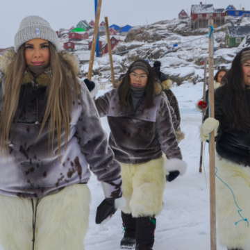 Three young women walking towards the camera surrounded by a snowlandscape in Greenland. They are wearing