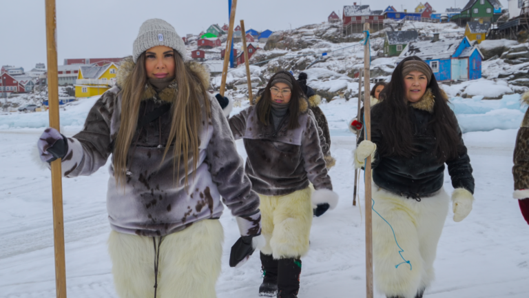 Three young women walking towards the camera surrounded by a snowlandscape in Greenland. They are wearing